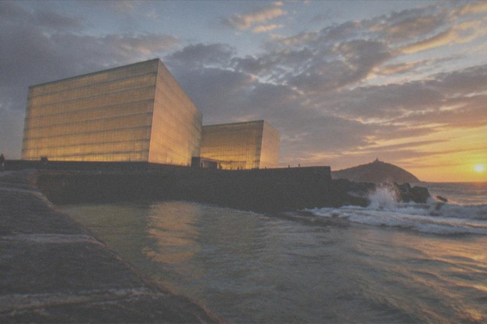 The illuminated Kursaal concert hall cubes beside the river mouth in San Sebastián at dusk