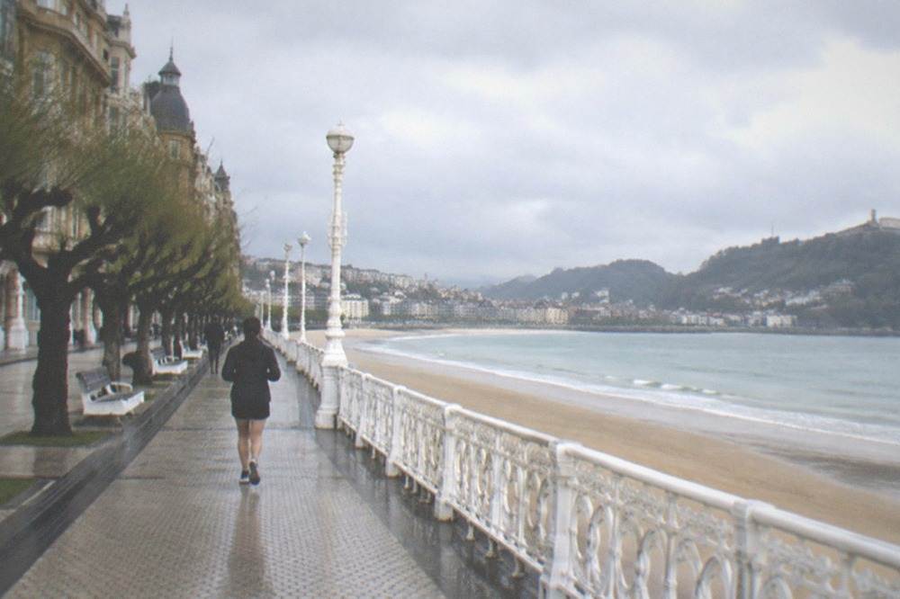 Rain clouds over a coastal city bay with a curved promenade