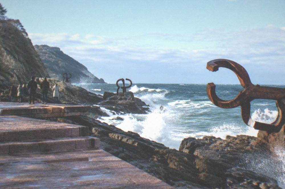 Waves breaking against the three steel sculptures of the Peine del Viento on the rocks at Ondarreta