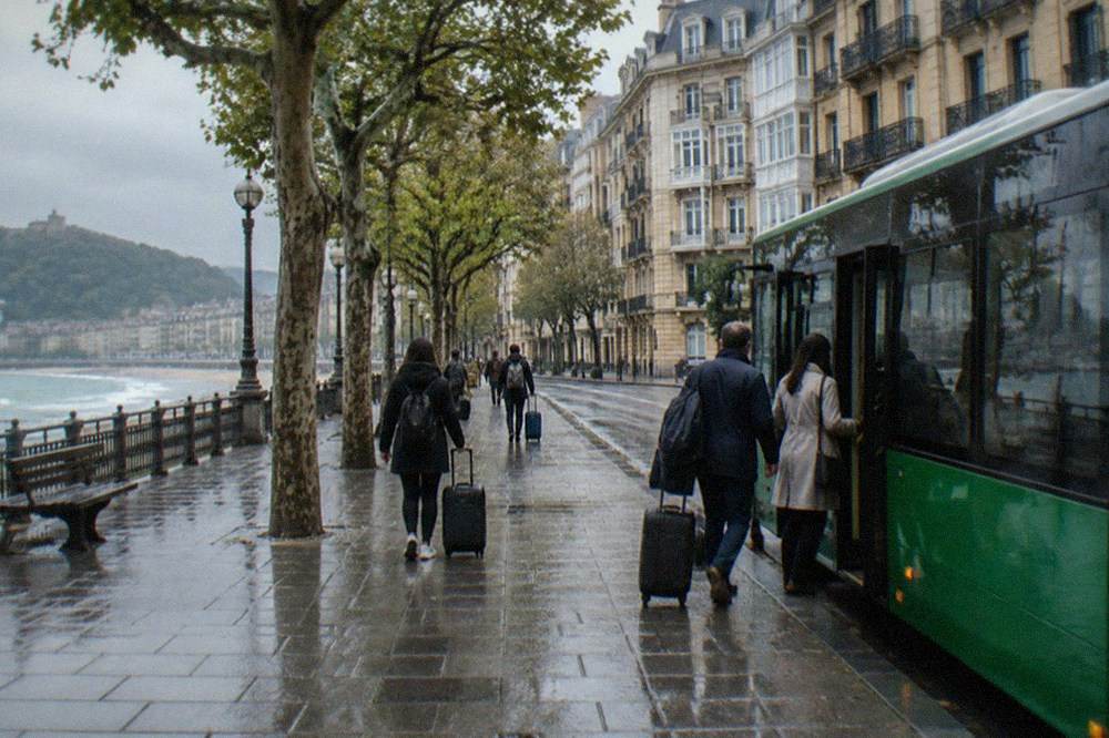 Passengers with luggage boarding a green Lurraldebus at a coastal Basque town stop