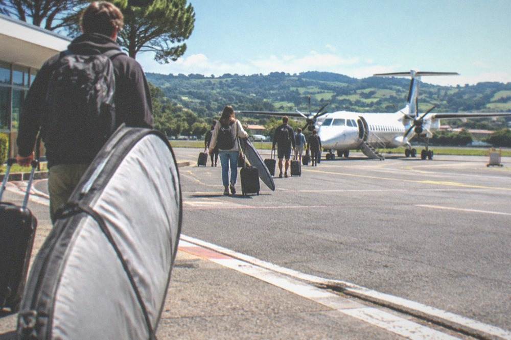 A small airplane on the tarmac at Biarritz airport with green hills behind