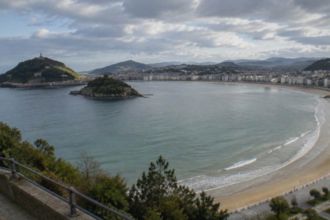 La Concha bay in San Sebastián seen from above on a calm morning, with the beach promenade and Santa Clara island in the distance