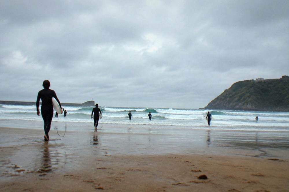 Zurriola beach in the Gros district with surf waves breaking and a wide sandy stretch at low tide