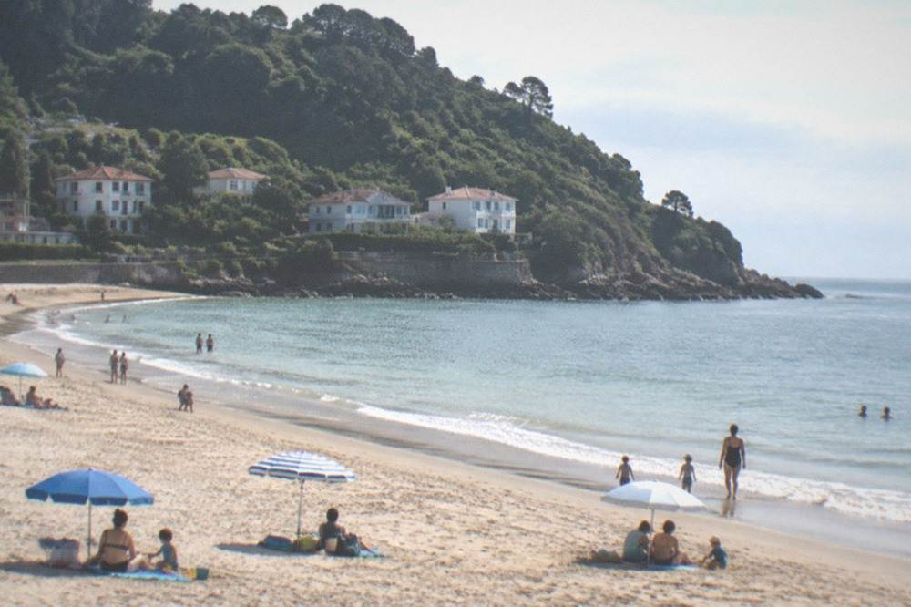 Families with children playing on the sand at Ondarreta beach with parasols and calm water