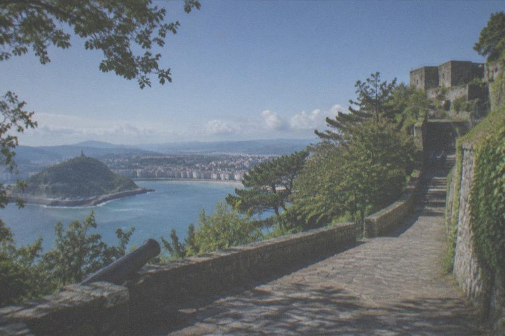 A stone path winding up the wooded slopes of Monte Urgull toward the Castillo de la Mota with views over the bay