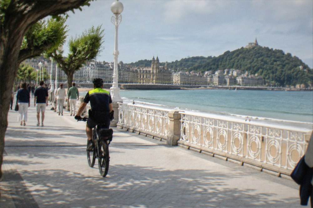 A police officer on a bicycle patrolling the seafront promenade of La Concha bay on a summer afternoon