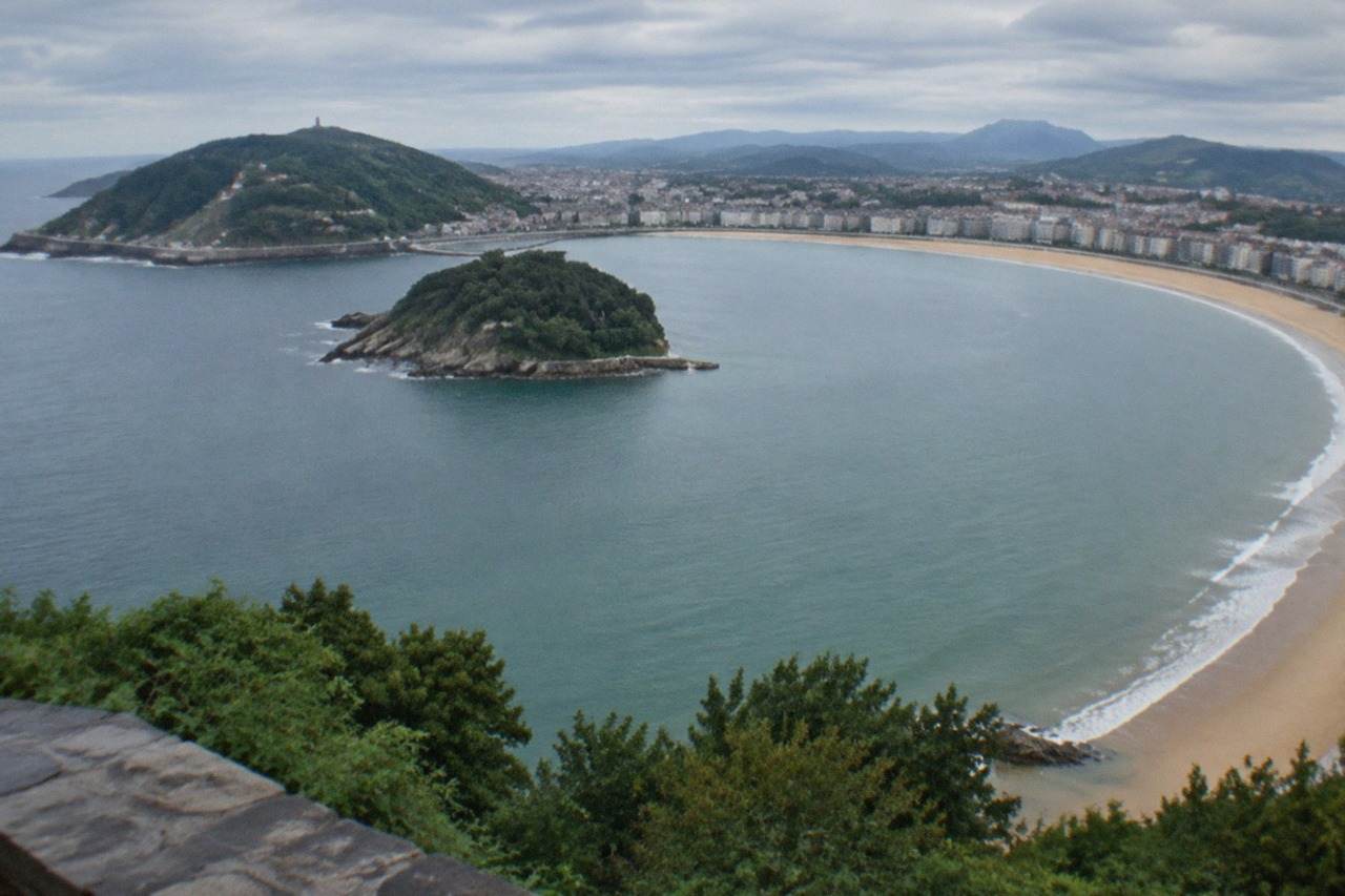 The curved sandy bay of La Concha seen from above, with Santa Clara island offshore and hills on either side
