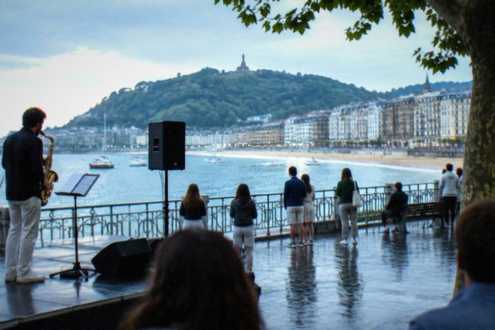 Saxophonist performing on an outdoor stage with a bay behind