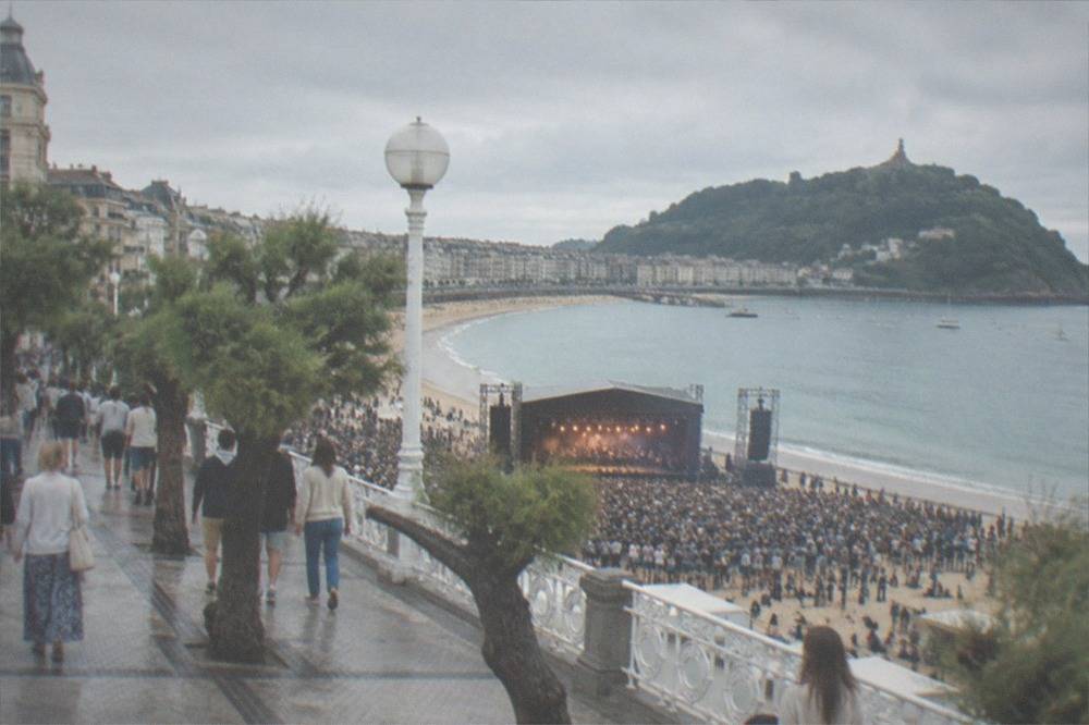 Evening crowd on a beach promenade in front of a stage