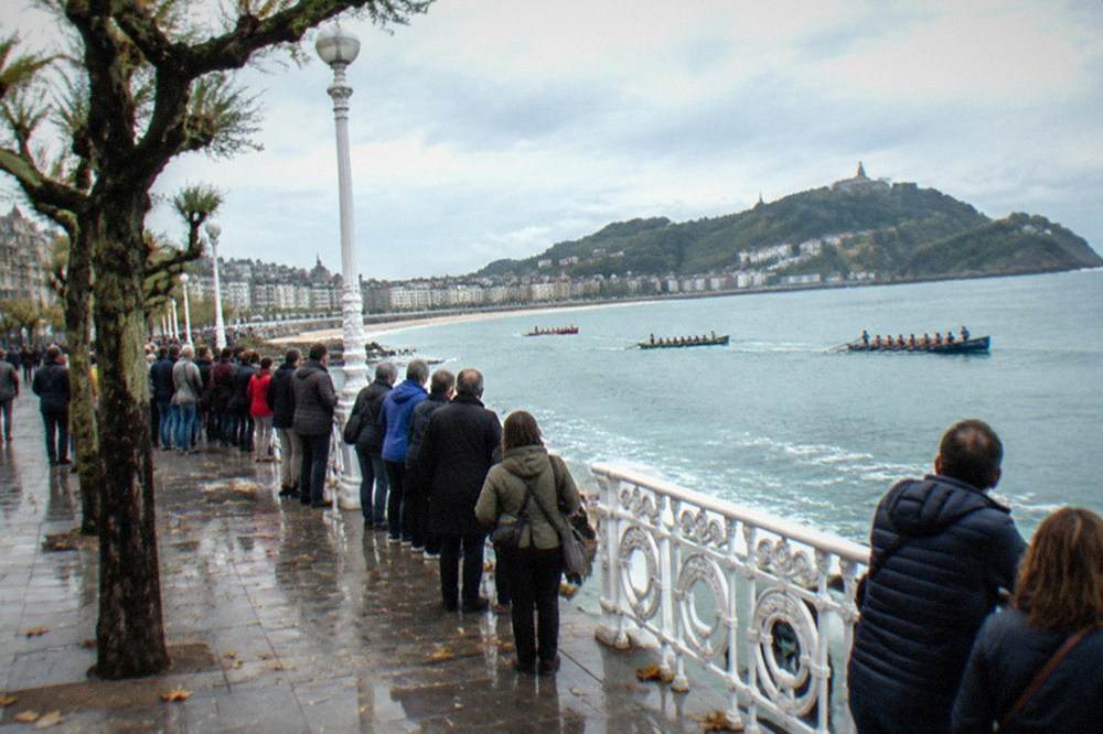Crowds standing several deep along the Paseo de la Concha railing watching traineras race below