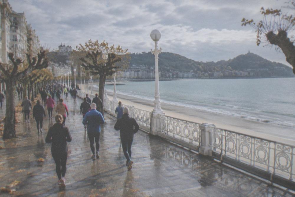 The Paseo de la Concha promenade filling with people walking toward the bay on a race morning