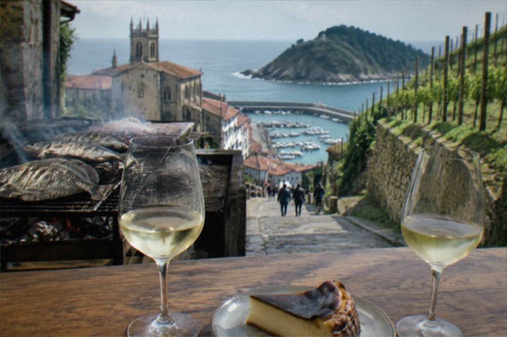 Two glasses of txakoli and a slice of burnt cheesecake on a wooden bar counter