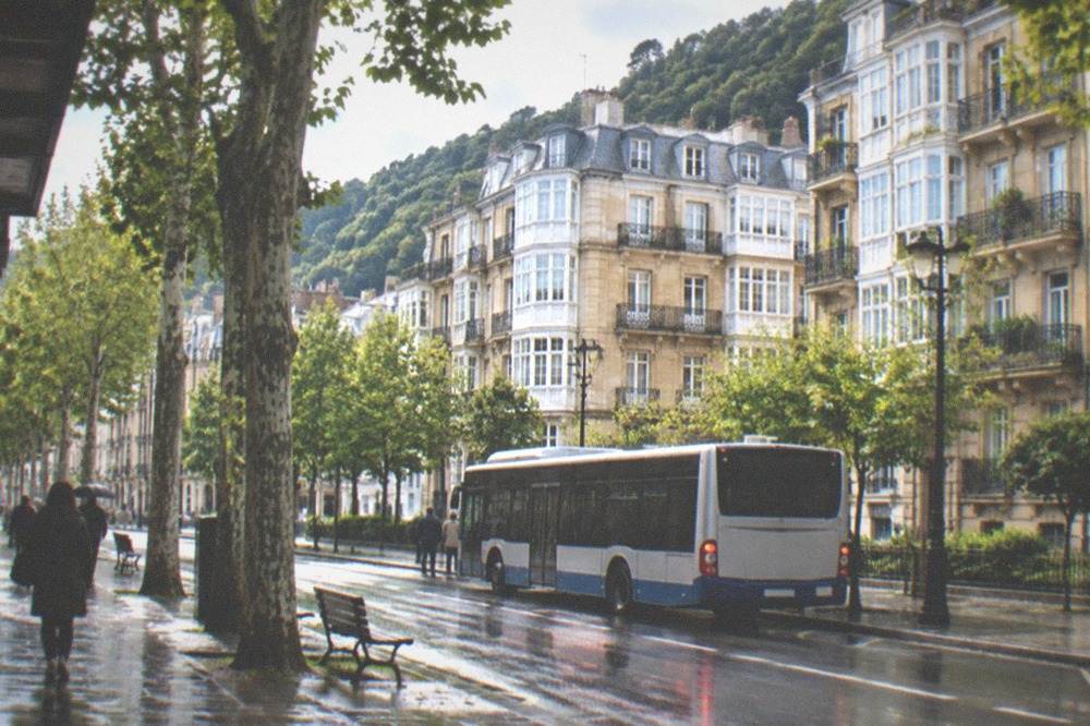 A city bus stopping on a tree-lined street in central San Sebastián