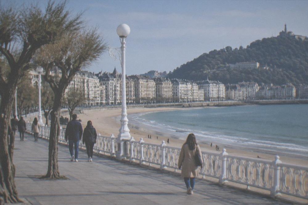 People walking along the promenade beside La Concha beach in the late afternoon