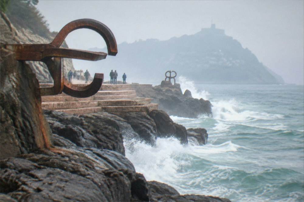 Waves breaking on the rocks at the Peine del Viento sculptures at the western end of the bay
