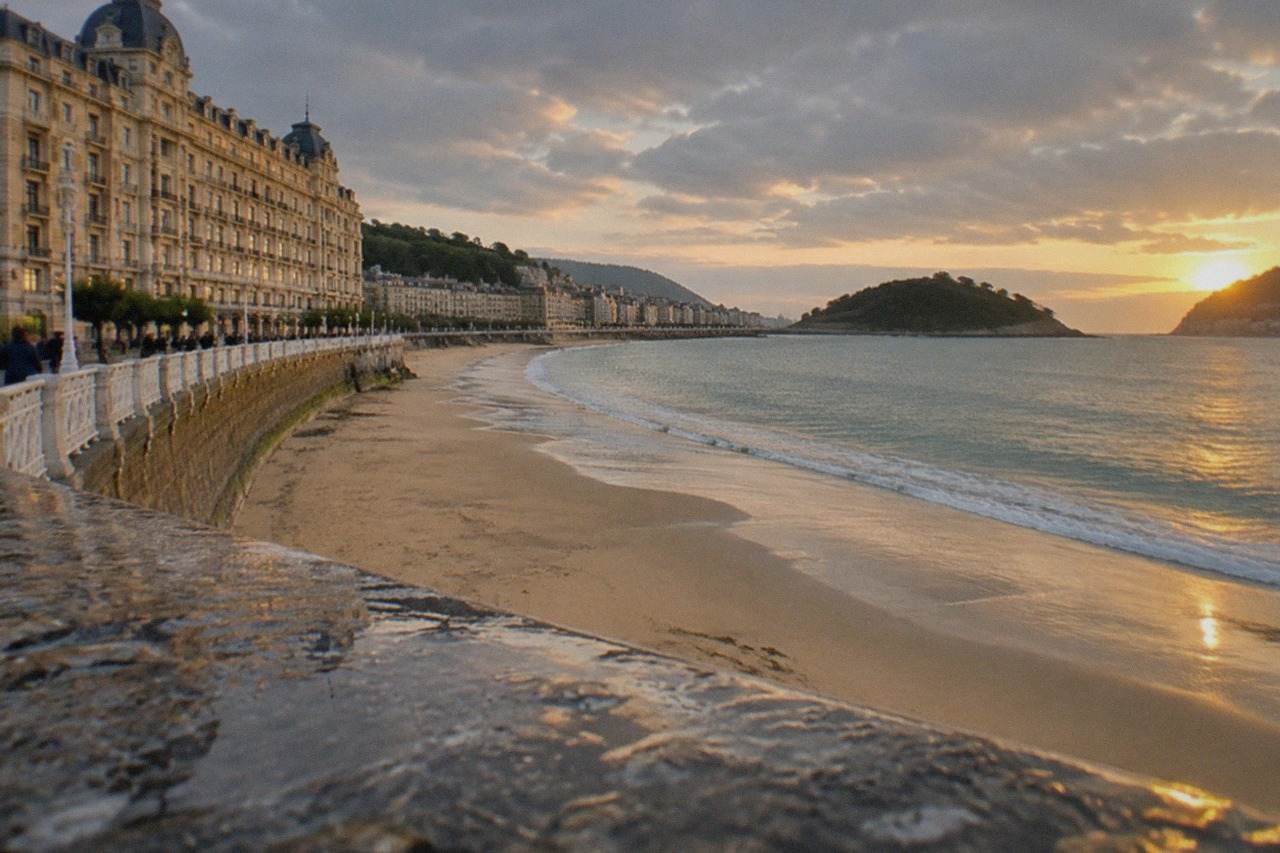 A grand bayfront hotel facade above La Concha beach in San Sebastián at golden hour