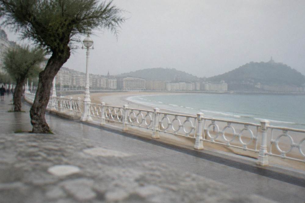 The curved promenade of La Concha with hotel facades and white railings above the sand