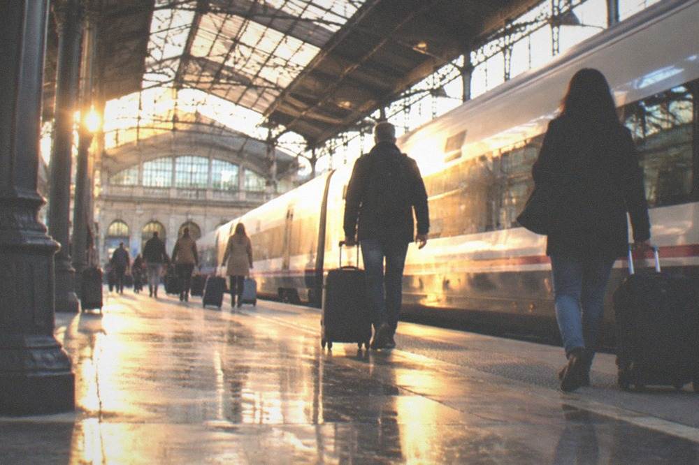 Travellers with suitcases walking along a platform at a Spanish railway station