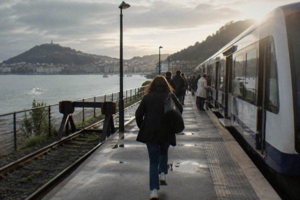 A narrow-gauge train at a small station platform beside a river estuary
