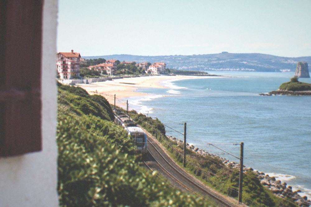 A coastal railway track curving beside a blue bay with a small island