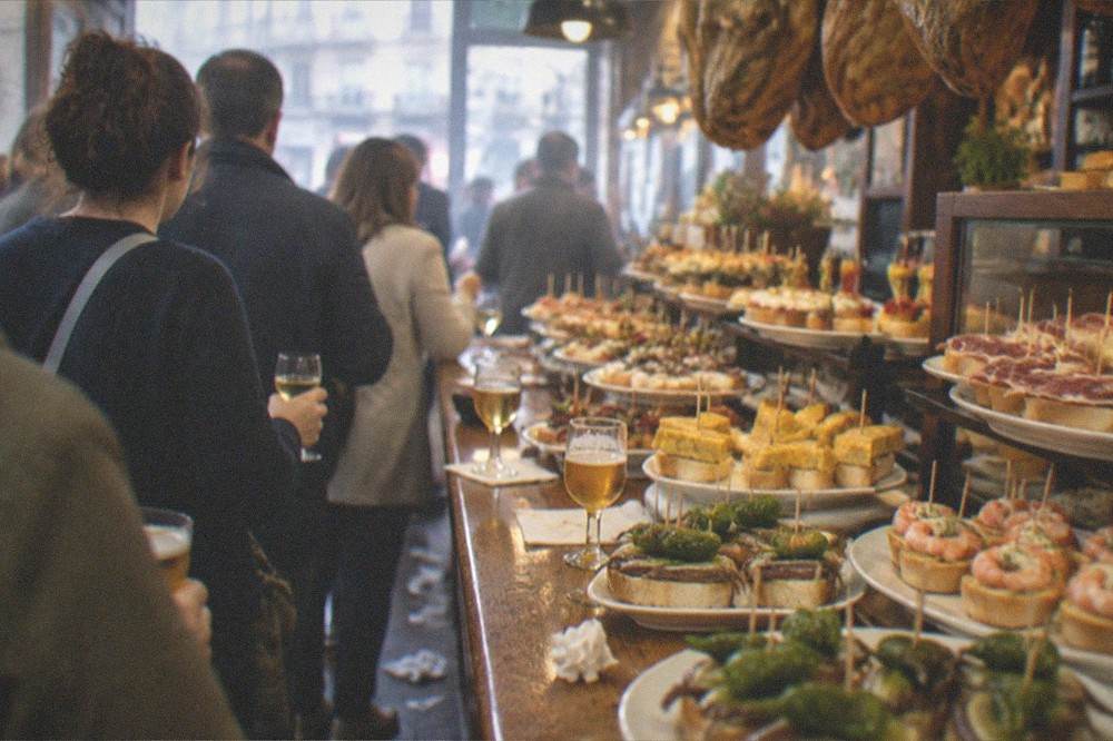A group standing at a bar counter with small plates and wine glasses