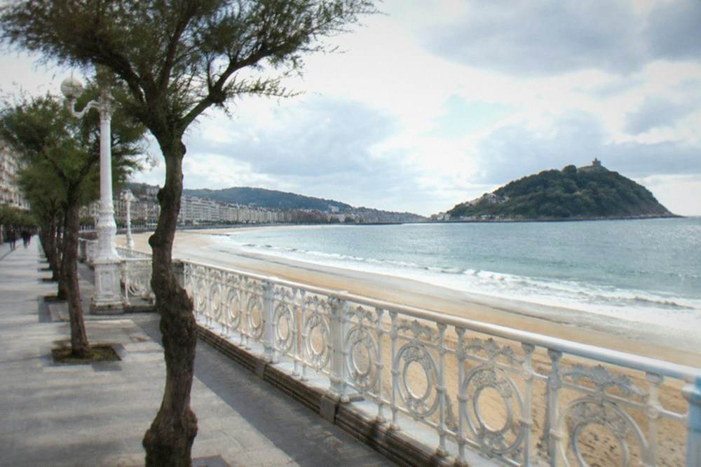 Palm-lined promenade beside La Concha bay with an island offshore