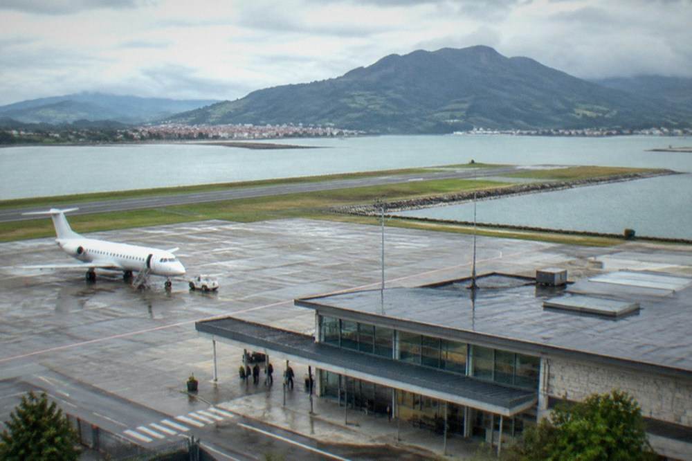 A small regional airport terminal building under a cloudy sky in the Basque Country