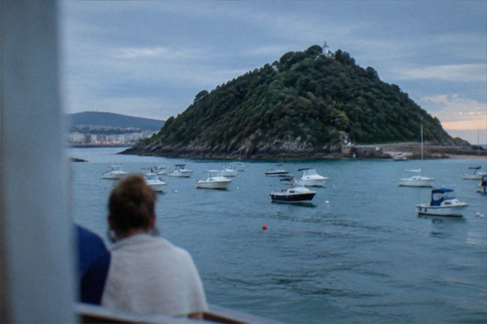 Small boats moored in La Concha bay with Santa Clara island in the background on a summer evening