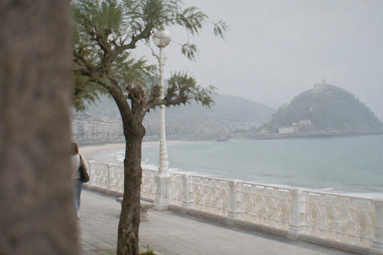 The wide seafront promenade of La Concha bay in San Sebastián with the island and hills behind