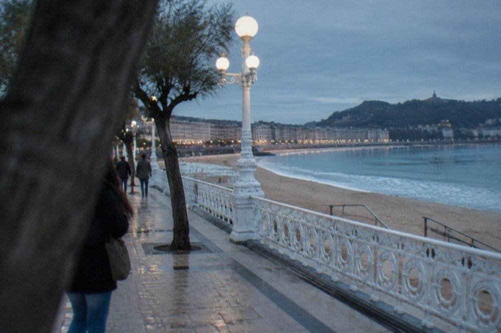A level stone promenade along La Concha beach with railings and beach access ramps