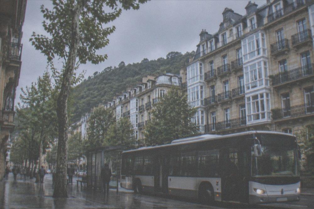 A modern city bus at a stop on a flat street in central San Sebastián