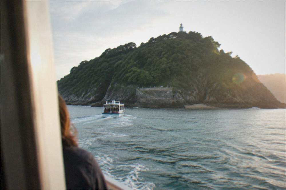 A small passenger boat approaching Santa Clara island across La Concha bay