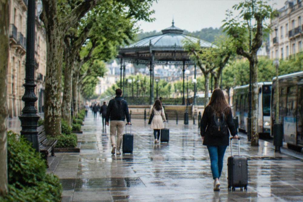 Travellers with suitcases walking across the Boulevard in central San Sebastián