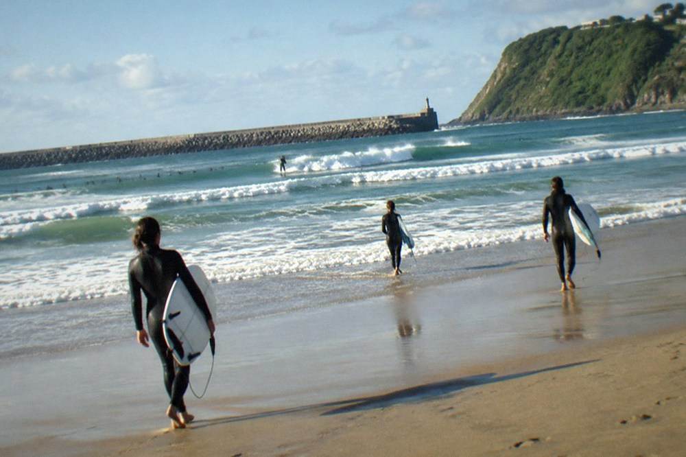 Zurriola beach in the Gros district with waves breaking and surfers in the water