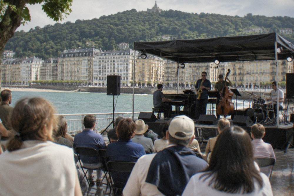 An open-air jazz stage by the sea in San Sebastián with a summer crowd listening