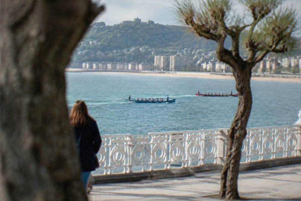 Two trainera rowing boats racing across La Concha bay watched from the promenade