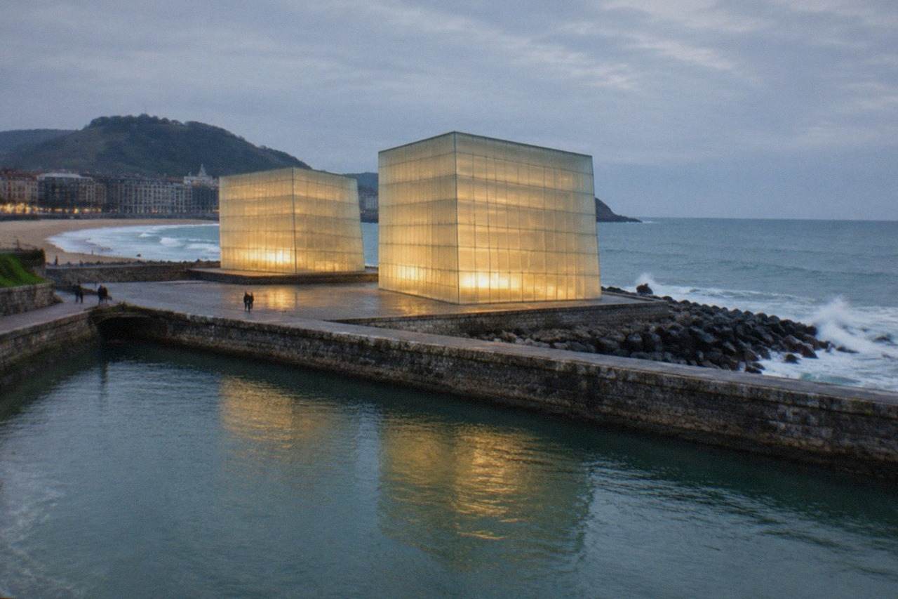 The illuminated Kursaal Congress Centre glass cubes beside the Urumea river in San Sebastián at dusk