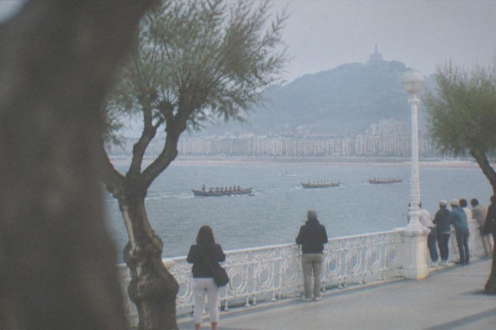 Traditional trainera rowing boats racing across La Concha bay watched by crowds on the promenade
