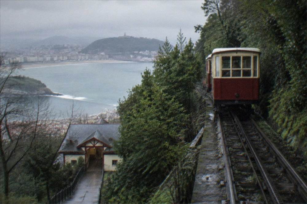 The wooden funicular car climbing the wooded slope of Monte Igueldo above the bay