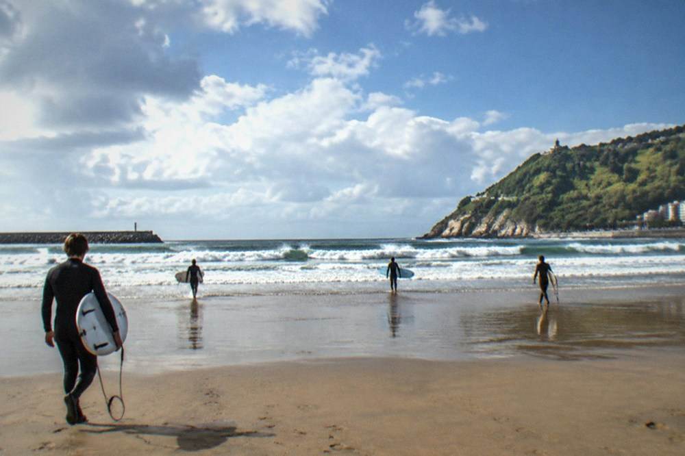 Zurriola beach with surfers in wetsuits and a fresh spring sky