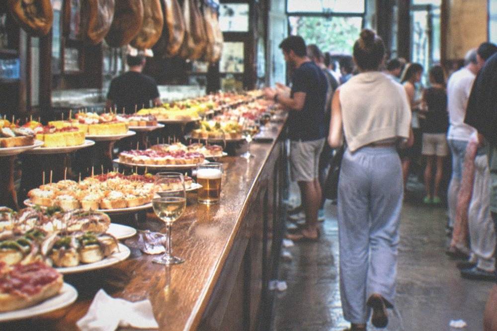 Crowded pintxo bar counters in the Old Town of San Sebastián on a summer evening