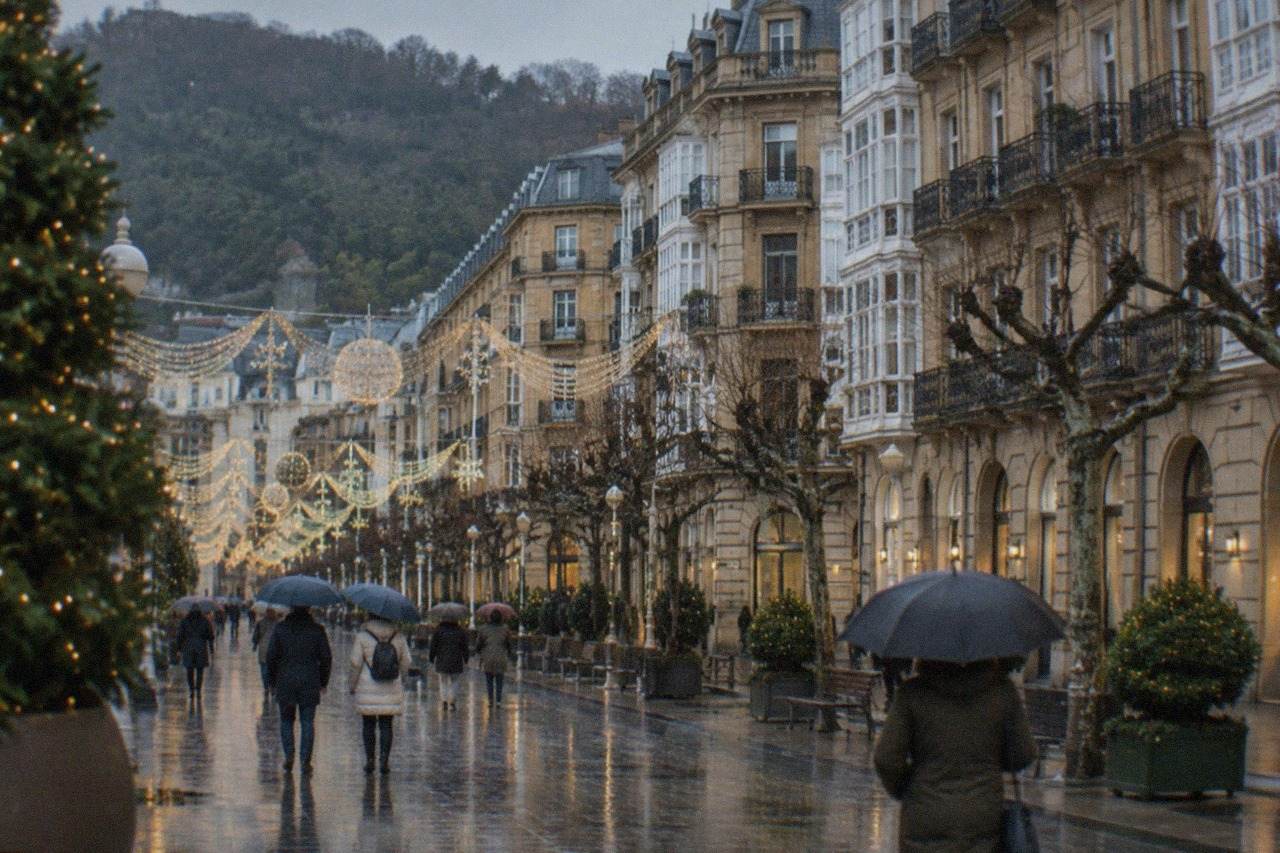 Christmas lights above a decorated street in San Sebastián at dusk, with people walking beneath the illuminations