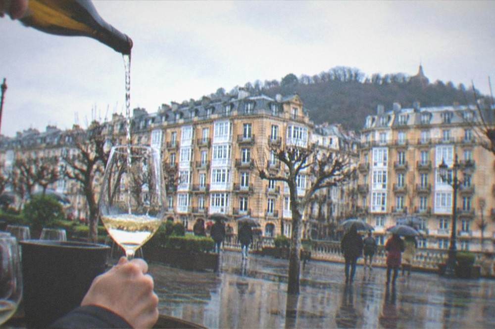 A white wine being poured from a height into a glass at a Basque winery tasting