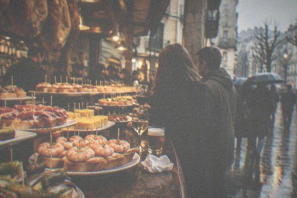 Pintxo bars in the Old Town at night with counters of small skewered dishes and people standing with drinks