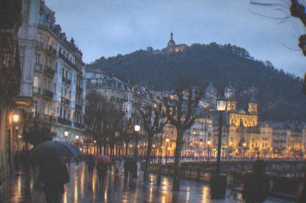 The illuminated Old Town at dusk in winter with the outline of Monte Urgull behind it