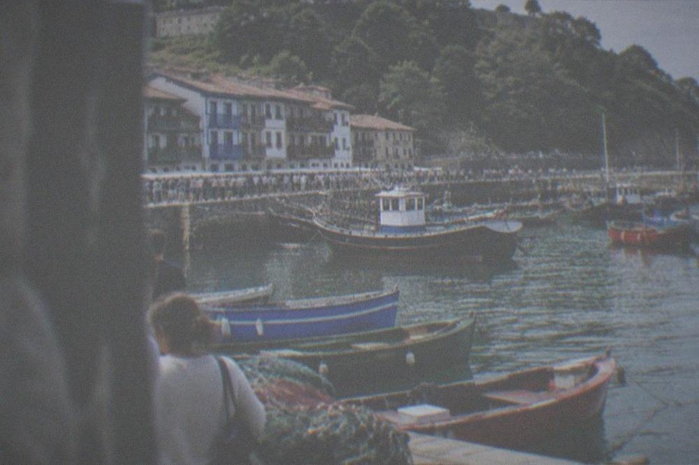 Traditional wooden fishing boats and a crowd along the harbour in San Sebastián on a summer regatta day