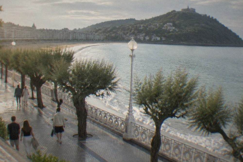 People walking along the La Concha promenade in San Sebastián with the bay and Monte Igueldo behind