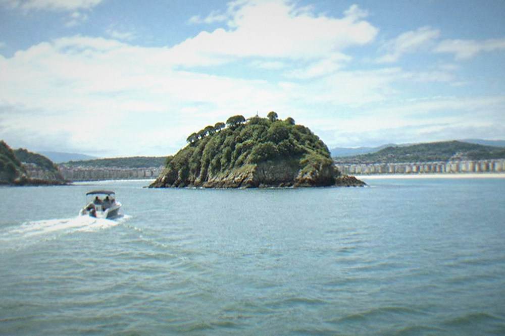 A small boat crossing La Concha bay toward Santa Clara island on a clear day