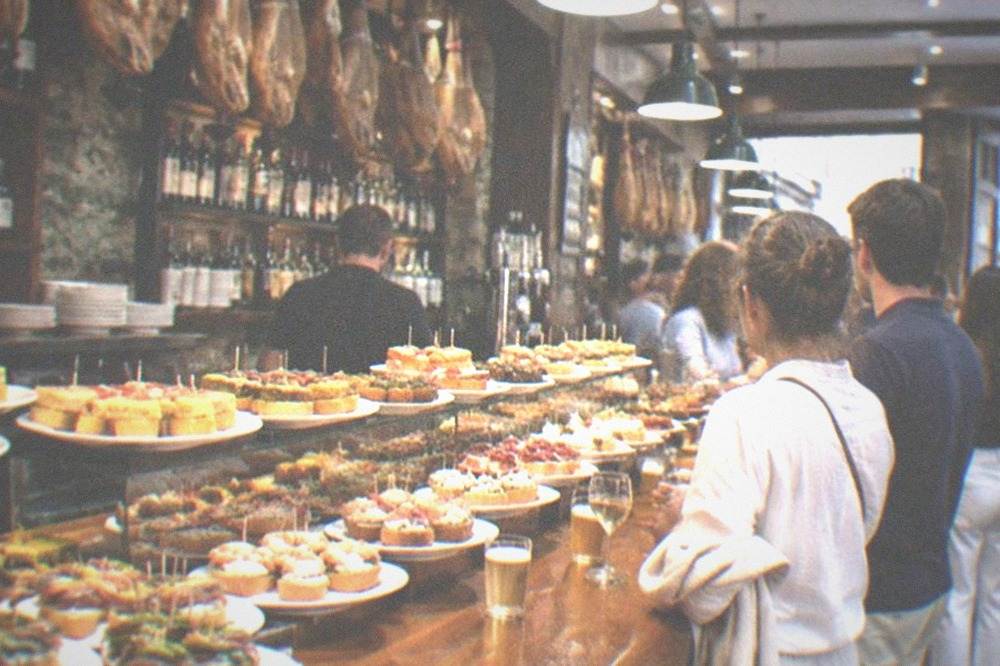 A pintxo bar counter in the Old Town of San Sebastián with skewered pintxos on display