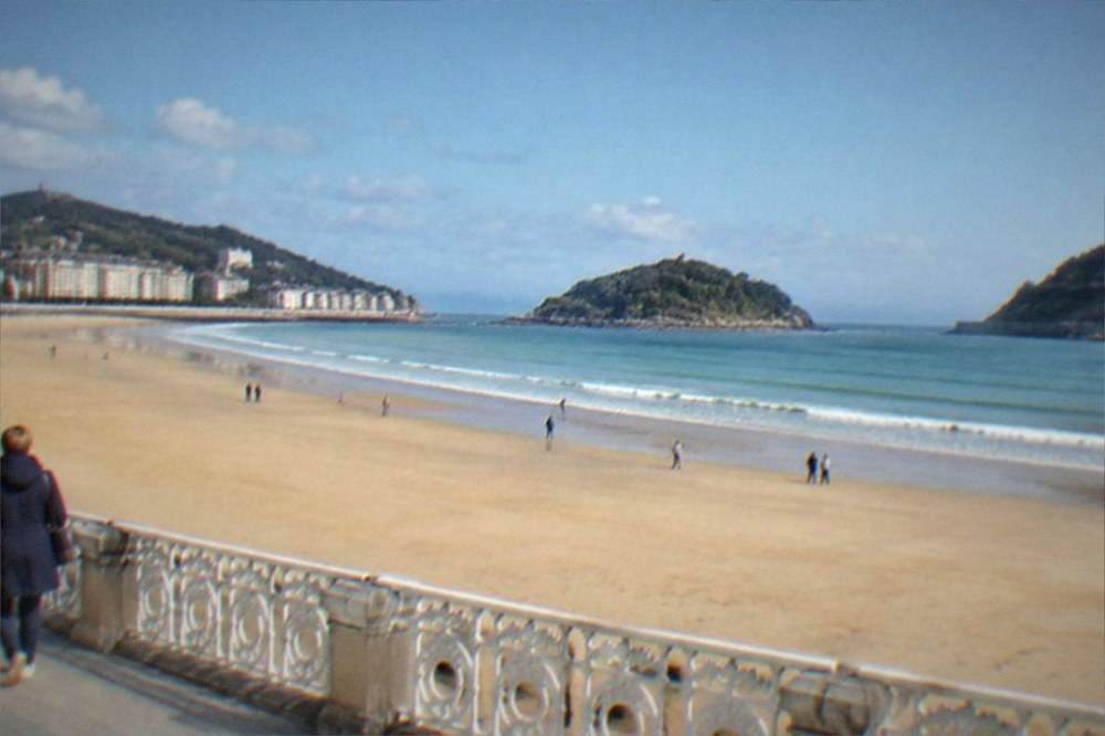 Walkers with light jackets on the coastal path above La Concha beach